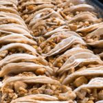 A lineup of chicken tacos filled with seasoned chicken, lettuce, and cheese